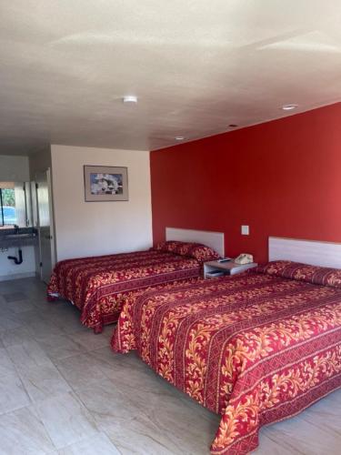 Cette chambre comprend 2 lits et un mur rouge. dans l'établissement Star Lodge Motel-Oceanside, à Vista