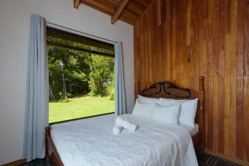 een slaapkamer met een bed en een groot raam bij HeCo House in Monteverde Costa Rica