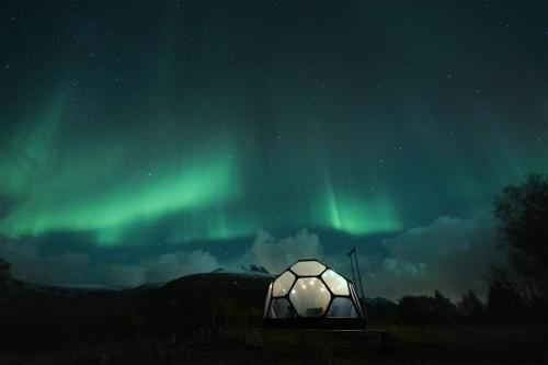 a tent under the northern lights in the sky at Bestefarhaugen - The cozy house on the hill - with a dome in Bø