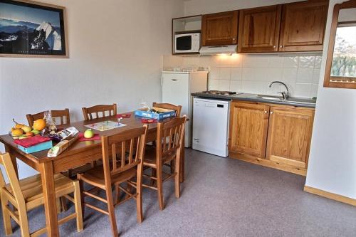une cuisine avec une table en bois et des chaises et une cuisine avec un évier dans l'établissement Cozy 6-person apartment with balcony, à Saint-Étienne-en-Dévoluy