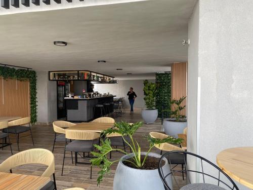 a restaurant with tables and chairs and a woman in the background at HOTEL PLAZUELA REAL in Bucaramanga