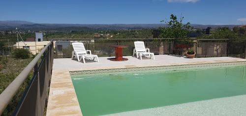 a swimming pool with two chairs and a table at Estancia de Campo in Estancia Vieja