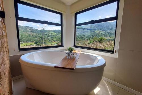 a bath tub in a bathroom with two windows at Monte Paraíso - banheira e vista da Pedra Menina in Espera Feliz