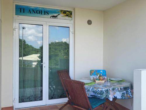 a table and a chair in a room with a balcony at le TI-ANOLIS tartane martinique in La Trinité