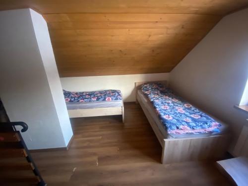 2 Betten in einem kleinen Zimmer mit Dachgeschoss in der Unterkunft Stawiska nad Tanwią - Roztoczański Hostel in Jędrzejówka