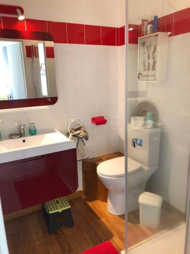 - une salle de bains rouge et blanche avec toilettes et lavabo dans l'établissement Ty Gabi - Maison à 20 minutes des plages, à Landaul