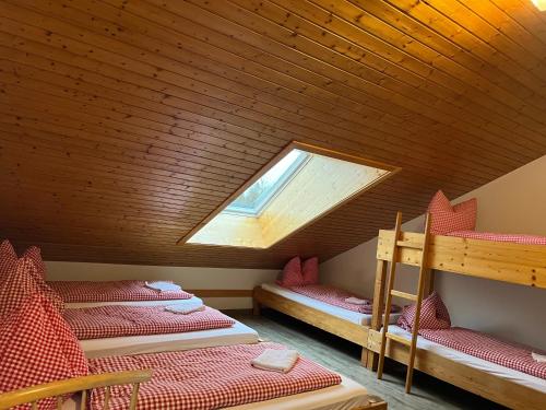 a attic room with three bunk beds and a window at Naturfreundehaus Brend in Neuweg