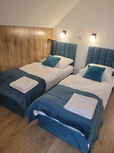 duas camas num quarto com azul e branco em Urocza Kryjówka ze SPA em Lesko