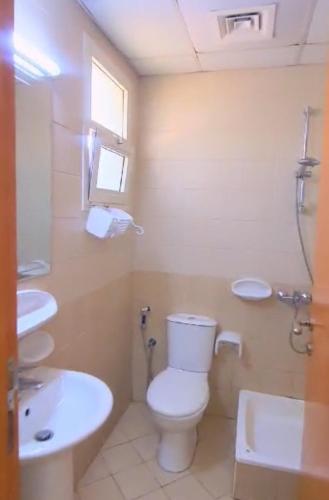 a bathroom with a white toilet and a sink at Studio bedroom flats in Dubai