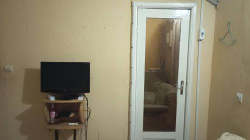 Zimmer mit einem TV und einer Tür zu einem Zimmer in der Unterkunft Julie-Appart in Brazzaville
