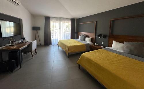 a hotel room with two beds and a desk at Hotel Boutique Abad in Guadalajara