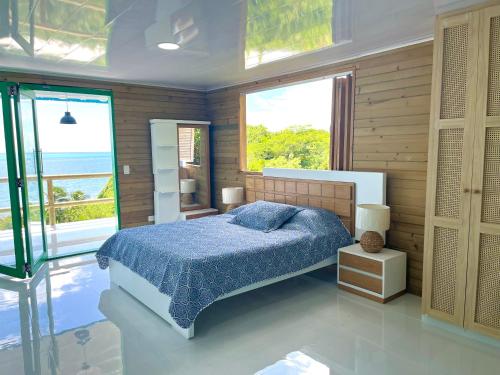 a bedroom with a bed with a blue comforter and windows at La Casita Azul Boutique Villa in Providencia