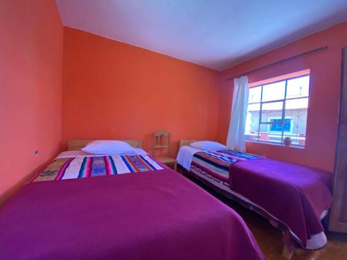 Duas camas num quarto com paredes vermelhas e uma janela em Orlando´s House em Ocosuyo