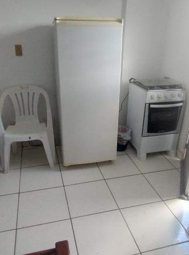 cocina blanca con nevera y silla en Edifício LaTorre, en Foz do Iguaçu