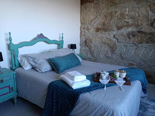 1 dormitorio con 1 cama con toallas y pared de piedra en Fraga`s House - Douro e Natureza en Coura