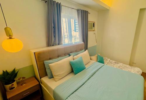 1 dormitorio con 1 cama con almohadas azules y blancas en The Loop 1-Bedroom sleeps 6, near Limketkai mall in Cagayan de Oro, en Cagayan de Oro