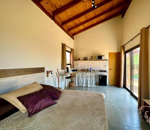 um quarto com uma cama grande e uma cozinha em Canastra - Chalés Canário de Minas em São João Batista do Glória
