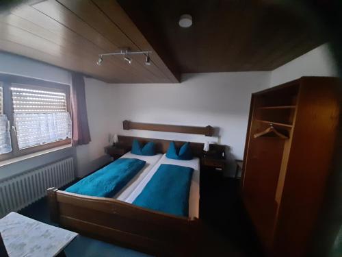 a bedroom with a large wooden bed with blue pillows at Gasthof Keller Merdingen in Merdingen