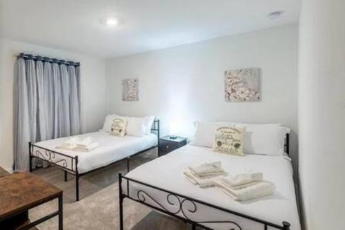 Cette chambre blanche comprend deux lits et une table. dans l'établissement 3308 - Gorgeous 3bed vacation home, à Kissimmee
