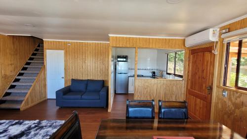 sala de estar con sofá azul y cocina en Cabañas con hermosa vista al río camino a Niebla, en Niebla