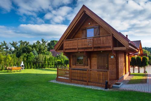 a log cabin with a deck on the grass at Górskie Wytchnienie in Jelenia Góra