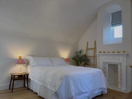 a bedroom with a white bed and a fireplace at Forge Cottage Suffolk in Sudbury