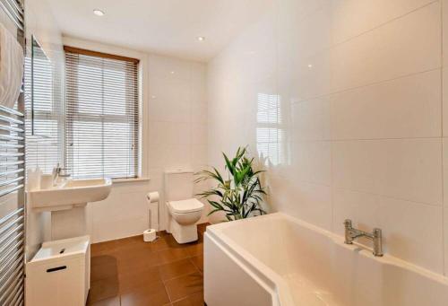 y baño con bañera, aseo y lavamanos. en Chatsworth Cottage en Harrogate