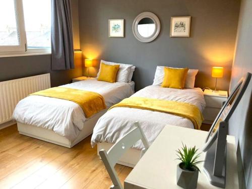 1 dormitorio con 2 camas y mesa con escritorio en Chatsworth Cottage en Harrogate
