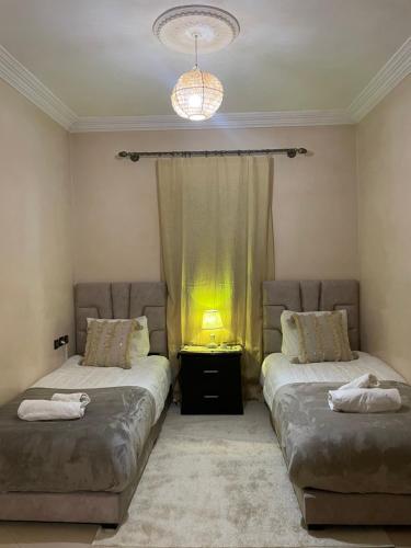 a bedroom with two beds and a window with a light at Kech Days appartement près de l'aéroport in Marrakesh