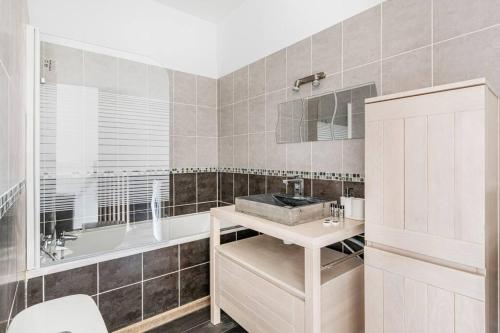 een badkamer met een bad, een wastafel en een bad tubermottermott bij Matilda - Hypercentre in Saint-Étienne