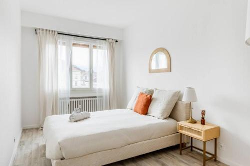 een witte slaapkamer met een bed en een raam bij Matilda - Hypercentre in Saint-Étienne