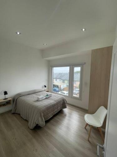 um quarto com uma cama, uma cadeira e uma janela em Apartament in the center Ushuaia two em Ushuaia