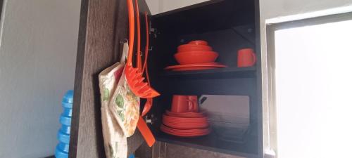 a cabinet filled with red plates and utensils at Hugo's Relax Home (Casa) in Ayangue