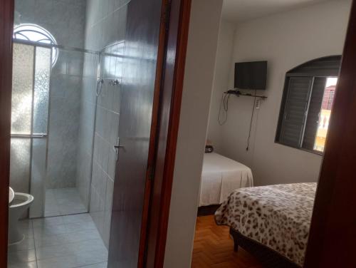 a bathroom with a shower and a bedroom with a bed at Casa Paraiso da Montanha in São Thomé das Letras