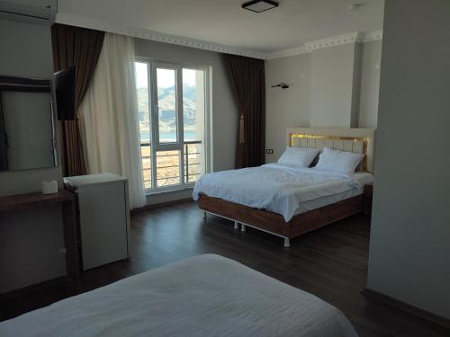 a bedroom with two beds and a large window at Hasankeyf Hasbahçe Otel in Hasankeyif
