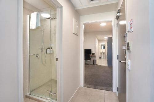 baño con ducha y puerta de cristal en Quality Suites Central Square en Palmerston North