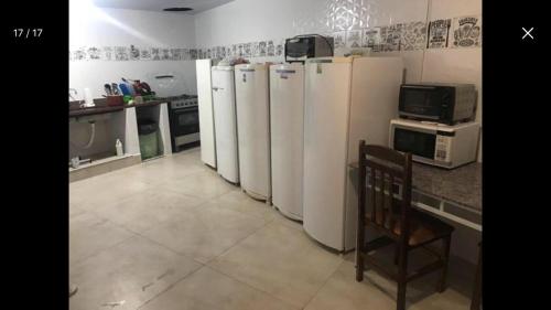 uma cozinha com uma fila de frigoríficos brancos em Hospedagem e kitnetes D' Itália em Curitiba