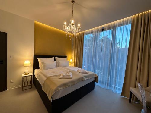 a bedroom with a bed with a chandelier and large windows at Villa Mala Praha Experience in the Center of Žilina in Žilina