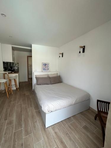 a bedroom with a white bed and a table at STUDIO avec PISCINE in Carmaux