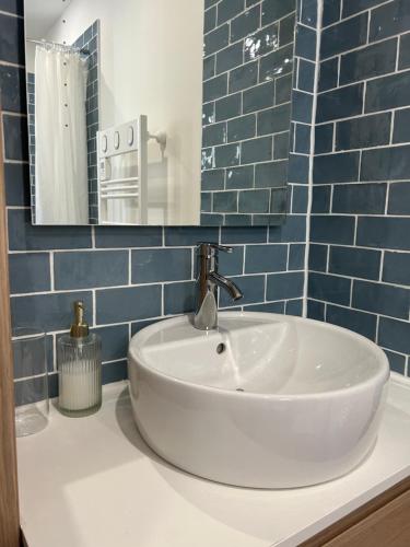 a bathroom with a sink and a mirror and blue tiles at STUDIO avec PISCINE in Carmaux