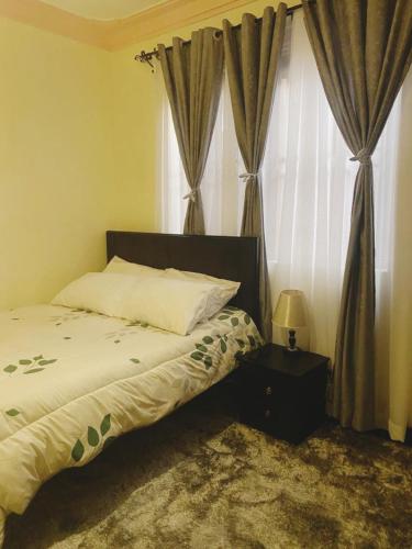 um quarto com uma cama e uma janela com cortinas em Kyaliwajala Heights Apartment em Kampala