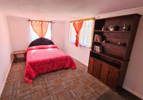 a bedroom with a bed with a red blanket at Refugio El Sauce in Curacaví