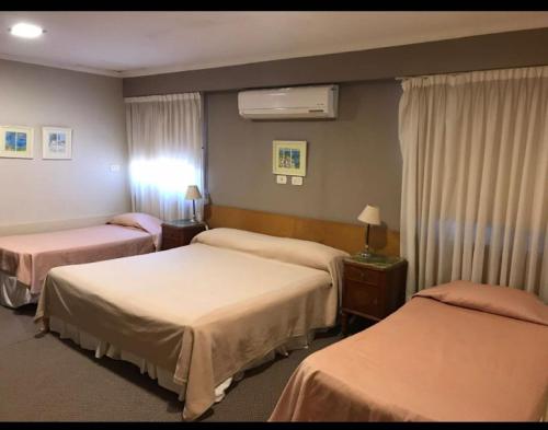 um quarto de hotel com três camas num quarto em Del Pomar Hotel Boutique em Resistência