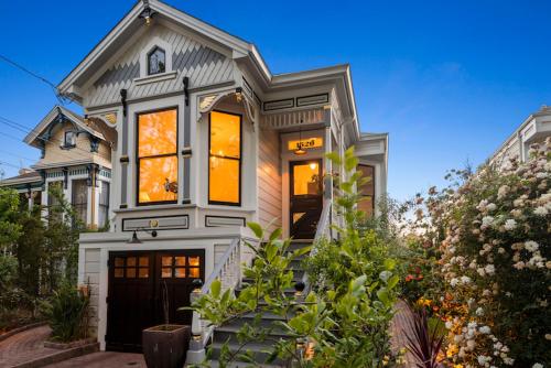 a white house with a black door at Minimalistic 1885 Queen Anne Cottage 2B-2B Upper Level Flat in Alameda in Alameda