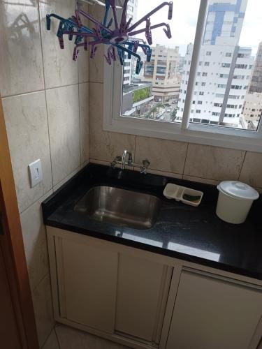 a kitchen sink and a window with a view of a city at APARTAMENTO SOLAR DA PRAÇA, Aconchegante, com ar condicionado,em frente ao shopping Vesta in Torres