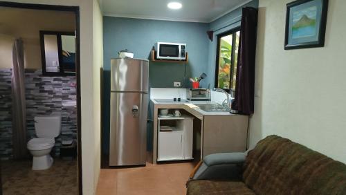 a small kitchen with a refrigerator and a sink at Granja Agua Azul.A/C WiFi,2 Camas, Rio, jardines. in Fortuna