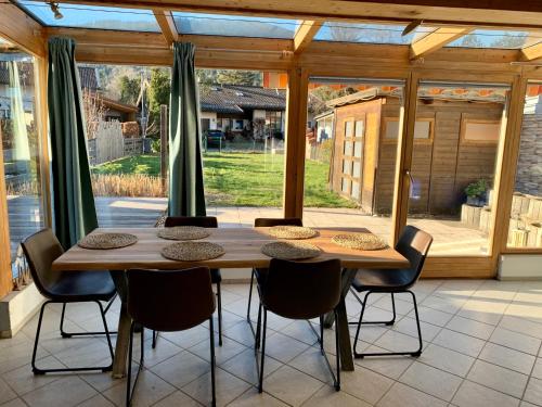 una mesa de madera y sillas en una habitación con ventanas en Kleines Reihenhaus im Chiemgau en Siegsdorf