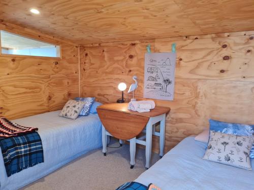 a room with two beds and a desk in a cabin at Pura Vida by the Sea in Riverton