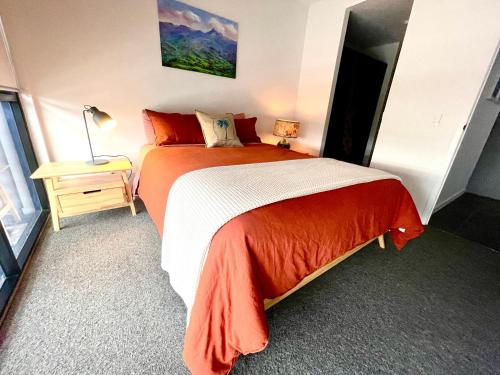 um quarto com uma cama com um cobertor laranja e branco em Ollies Place em Gold Coast