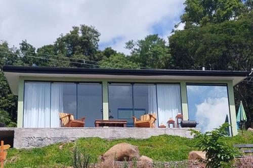 ein kleines Haus mit Glasfenstern und einer Terrasse in der Unterkunft Bem Vindo Ao Presente in Igrejinha